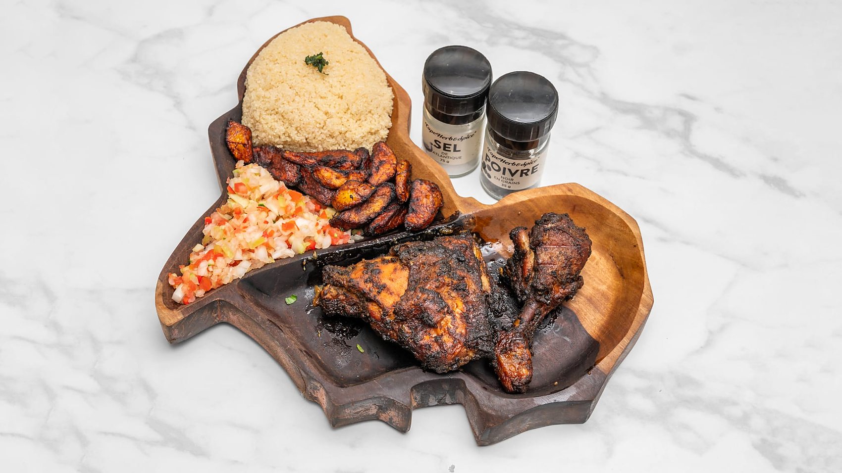 Poulet grillé mariné aux épices africaines, attiéké, aloko et salade tomate-oignon sur planche en forme d'Afrique